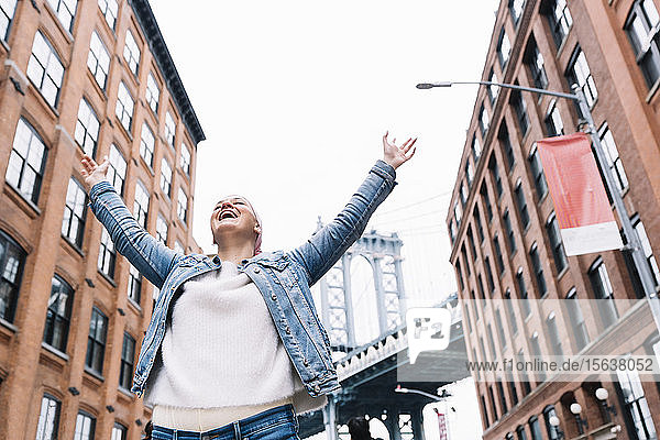 Frau mit Krebstuch und erhobenen Armen an der Manhattan Bridge in New York  USA