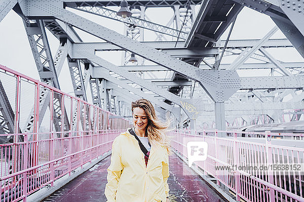 Eine Frau im gelben Regenmantel  die auf einer Brücke geht und nach unten schaut  New York  USA