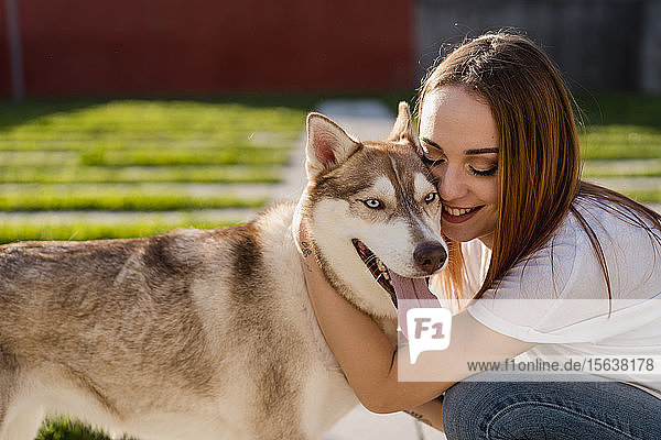 Glückliche junge Frau kuschelt mit ihrem Hund