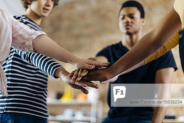 Young people standing together stacking hands