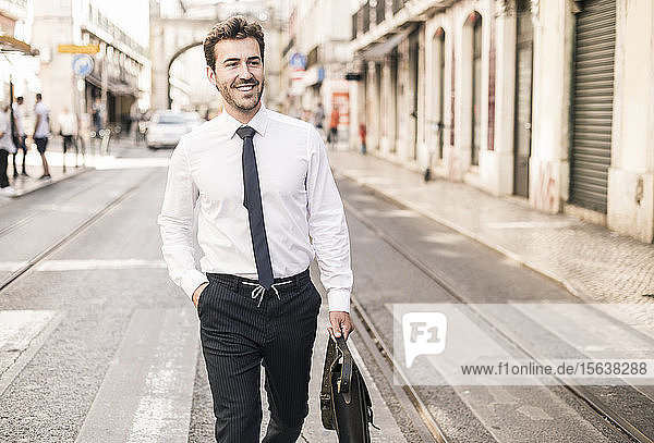 Lächelnder junger Geschäftsmann in der Stadt unterwegs  Lissabon  Portugal