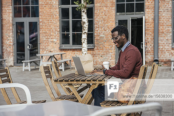 Young man using laptop in a coffee shop  drinking coffee