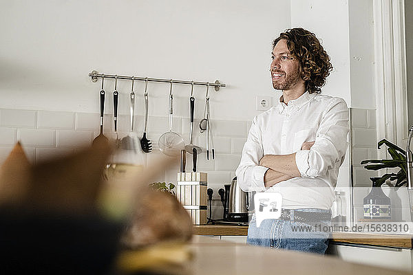 Lächelnder Mann steht zu Hause in der Küche