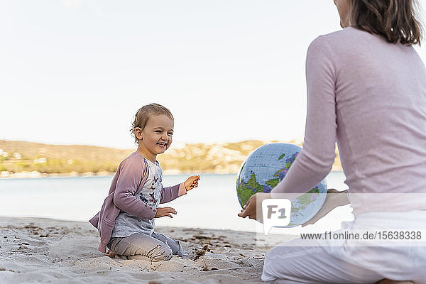 Porträt eines lachenden kleinen Mädchens beim Spielen mit dem Earth-Beachball