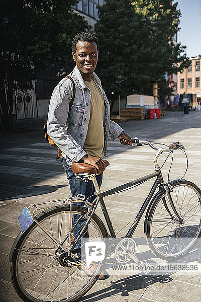 Zoung Mann pendelt in der Stadt  schiebt sein Fahrrad