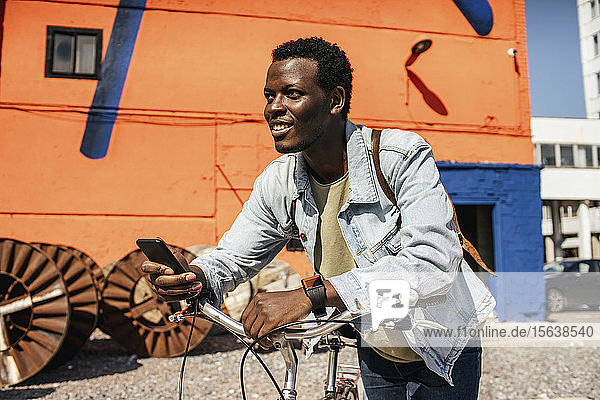 Entspannte junge Leute pendeln in der Stadt mit dem Hos-Fahrrad  mit Smartphone