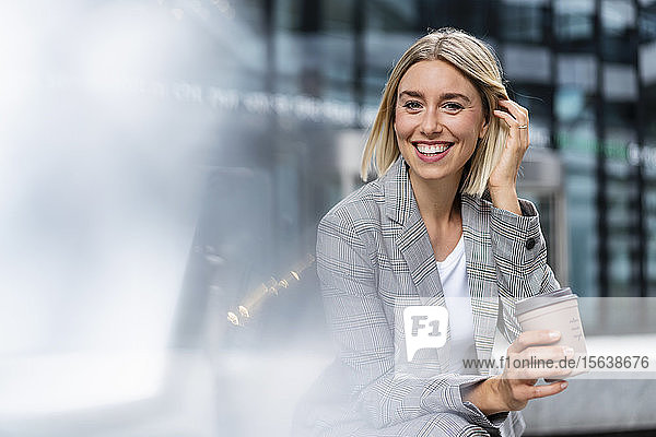 Porträt einer glücklichen jungen Geschäftsfrau mit Kaffee zum Mitnehmen in der Stadt