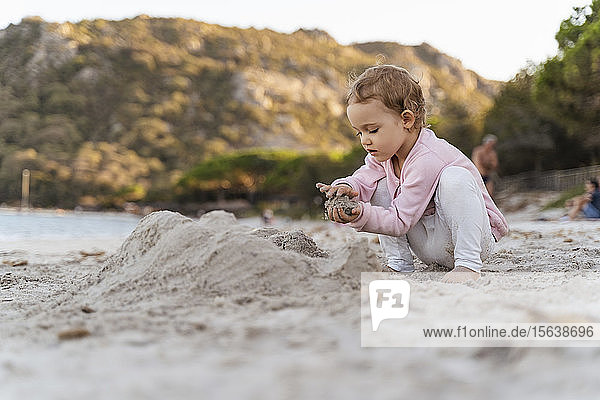 Süßes Kleinkind spielt mit Sand am Strand