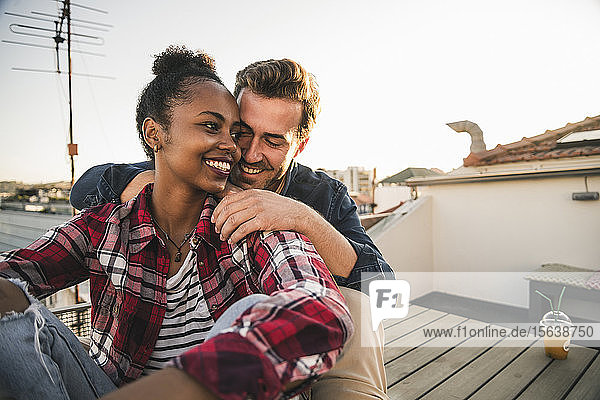 Glückliches  liebevolles junges Paar sitzt abends auf dem Dach
