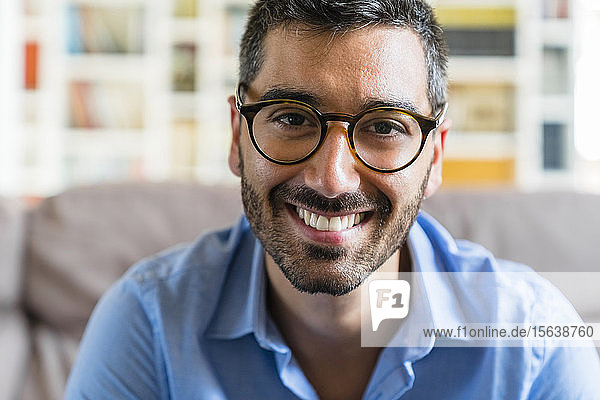 Porträt eines glücklichen jungen Mannes  der zu Hause eine Brille trägt