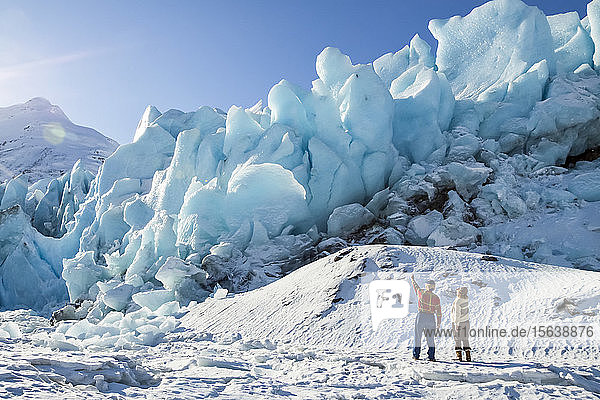 Hikers on the edge of frozen Portage Lake and looking at the Portage Glacier ice  South-central Alaska and South of Anchorage; Alaska  United States of America