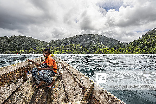 Papuan boy on a boat on the Warsambin River; West Papua  Indonesia