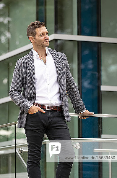 Geschäftsmann steht vor einem Gebäude und schaut weg; Vancouver  British Columbia  Kanada