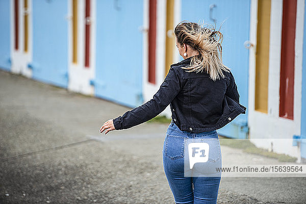 Eine junge Frau geht mit wehendem Haar und eng anliegenden Jeans die Straße entlang; Wellington  Nordinsel  Neuseeland