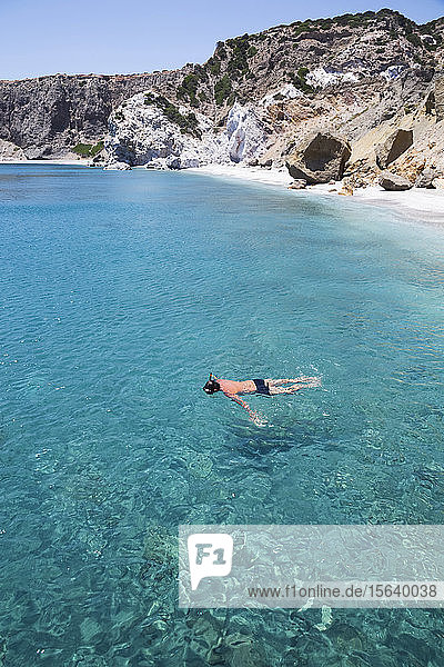 Male tourist snorkeling in the clear  turquoise water of Galazia Nera Bay; Polyaigos Island  Cyclades  Greece