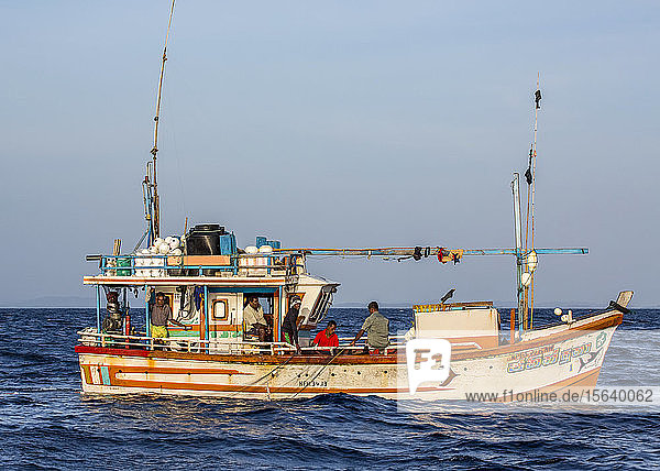 Sri Lankische Fischer ziehen ihr Netz über die Bordwand ihres Bootes im offenen Meer; Sri Lanka