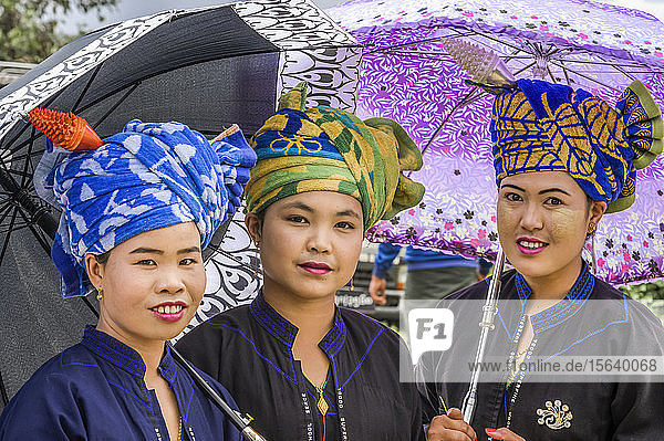 Frauen des Pa'O-Stammes  die eine bunte Kopfbedeckung tragen und mit Regenschirmen stehen; Yawngshwe  Shan-Staat  Myanmar