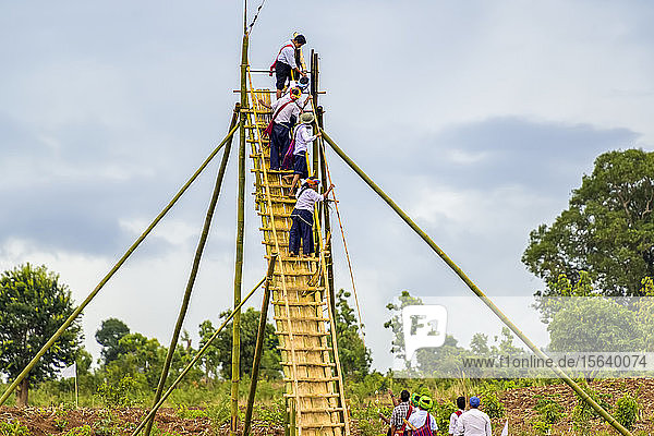 Männer klettern während eines Festes mit einer Rakete auf ein Gebäude  Pa'O-Stamm; Yawngshwe  Shan-Staat  Myanmar