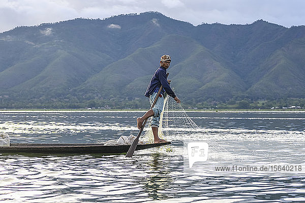 Traditioneller Fischer  der mit Netz und Paddel auf der Spitze des Bootes steht; Yawngshwe  Shan-Staat  Myanmar