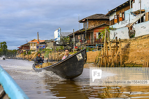 Boat with two passengers in the river along the shoreline; Yawngshwe  Shan State  Myanmar
