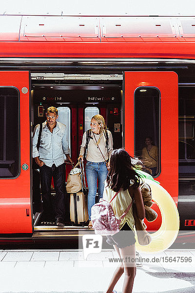 Tochter sieht Eltern beim Aussteigen aus dem Zug am Bahnhof