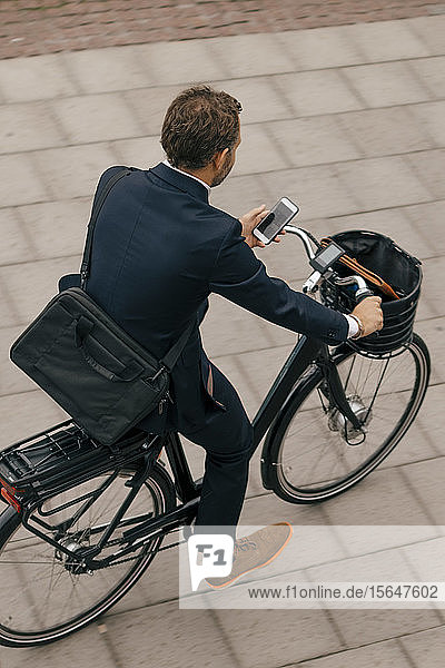 Hochwinkelansicht eines Geschäftsmannes auf dem Fahrrad auf einem Fußweg in der Stadt