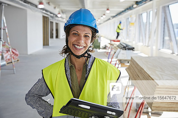 Porträt einer lächelnden Ingenieurin mit digitalem Tablett auf der Baustelle stehend