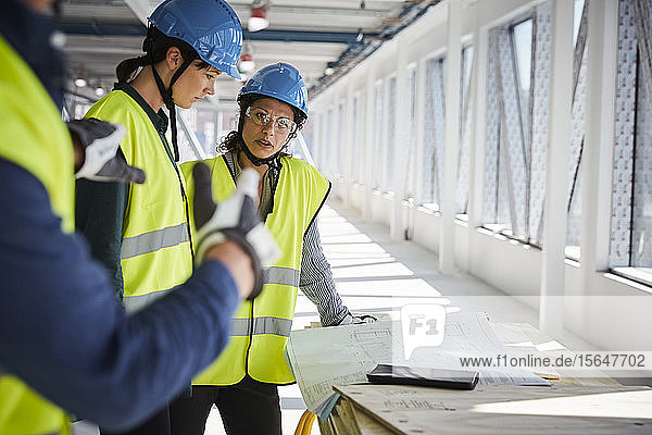Weibliche und männliche Ingenieure diskutieren auf der Baustelle über Baupläne
