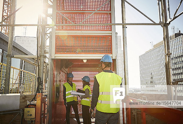 Männliche und weibliche Ingenieure am Lastenaufzug auf der Baustelle