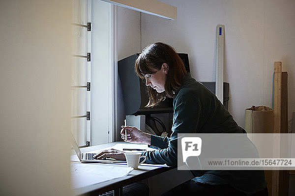 Seitenansicht einer selbstbewussten Architektin mit Laptop im Büro