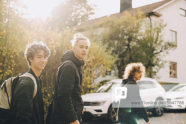 Portrait of smiling friends walking together in city during autumn