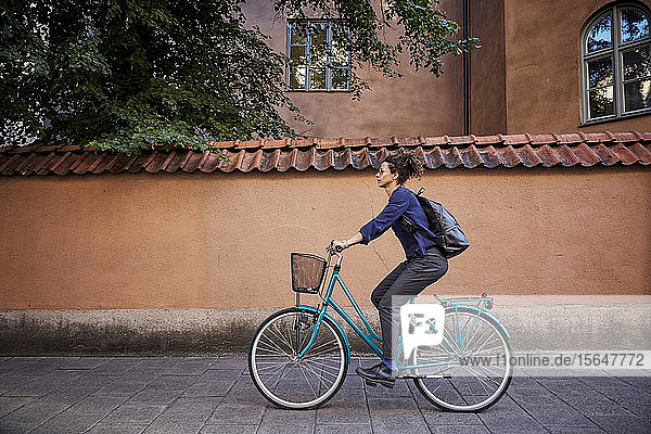 Side view of female architect riding bicycle on street in city