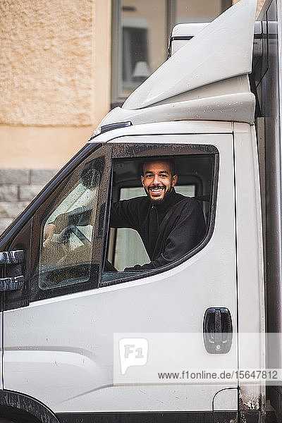 Portrait of smiling male mover driving truck