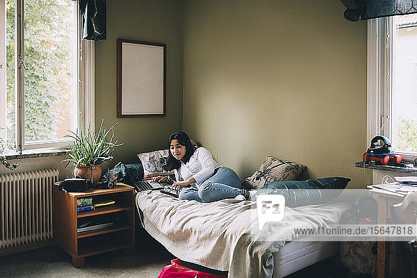 Teenager in voller Länge nutzt die Technologie  während er zu Hause im Bett liegt