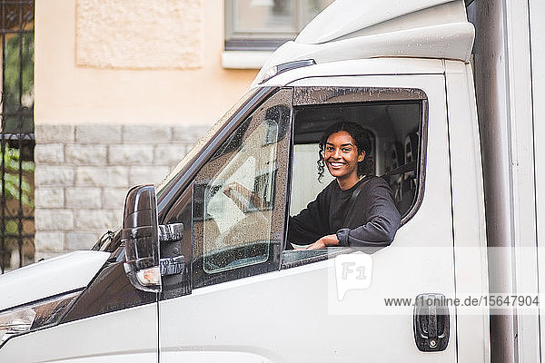 Porträt einer lächelnden Möbelpackerin am Steuer eines Lastwagens