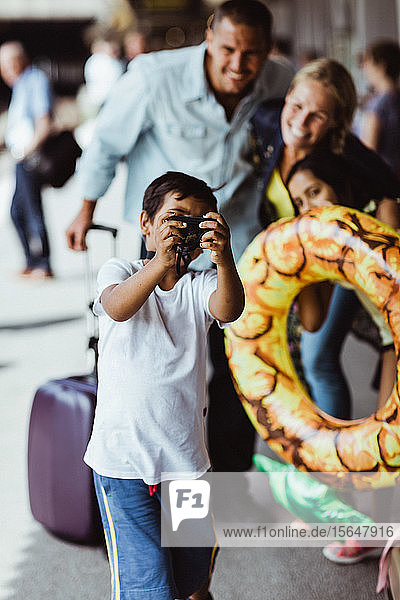 Junge nimmt sich mit seiner Familie während der Ferien am Bahnhof vor der Kamera