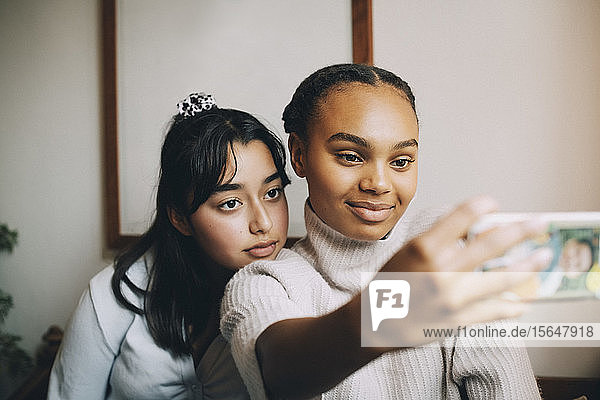 Teenage girls taking selfie with smartphone at home