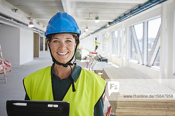 Porträt einer lächelnden Ingenieurin in reflektierender Kleidung auf einer Baustelle