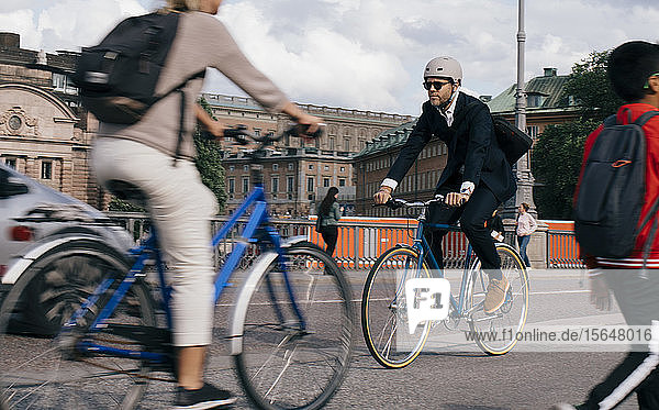 Geschäftsmann in voller Länge mit dem Fahrrad auf der Straße in der Stadt