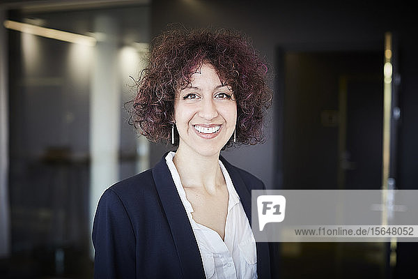 Porträt einer lächelnden Rechtsanwältin mit lockigem Haar im Büro