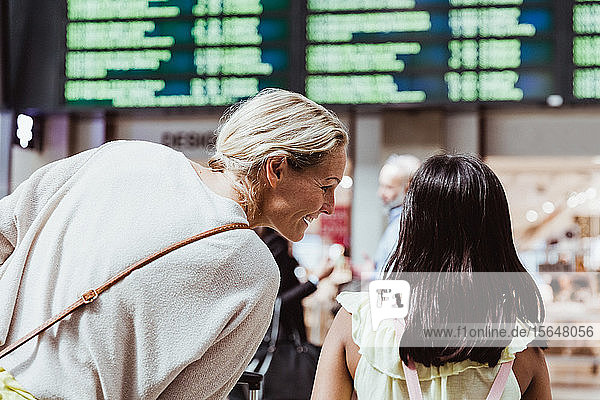 Rückansicht der lächelnden Mutter im Gespräch mit der Tochter am Bahnhof