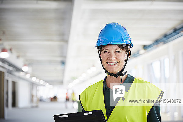 Porträt einer lächelnden Bauleiterin in reflektierender Kleidung auf der Baustelle