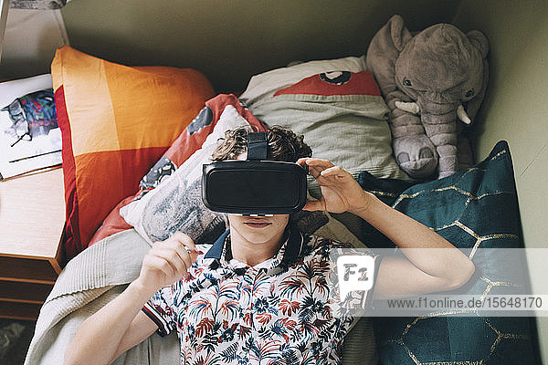Teenager-Junge mit Virtual-Reality-Headset  der zu Hause im Bett liegt