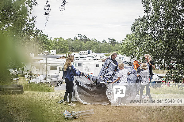Familie stellt während der Sommerferien gemeinsam ein Zelt auf dem Campingplatz auf
