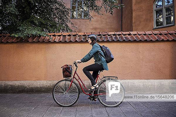 Seitenansicht einer Ingenieurin beim Fahrradfahren auf der Straße in der Stadt
