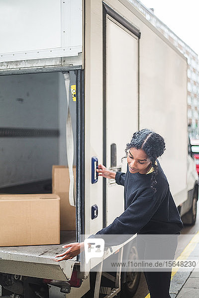 Spediteurin öffnet Tür eines Lastwagens auf der Straße in der Stadt