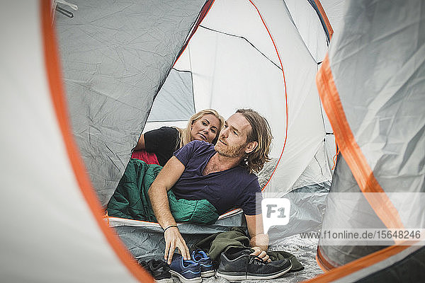 Ein Paar  das beim Zelten durch das Zelt schaut  während es sich im Schlafsack lehnt