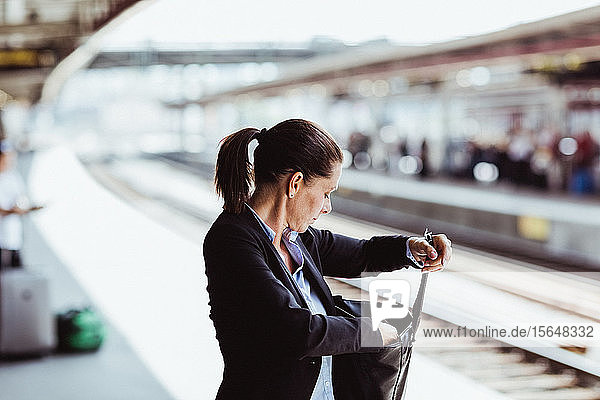 Mature businesswoman searching in bag at train station
