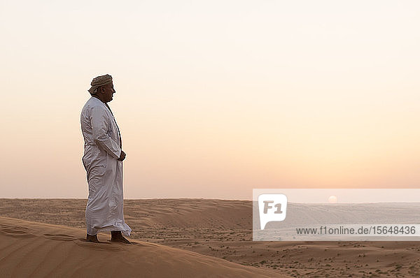 Omanischer Mann steht auf Sanddünen  Wüste Wahiba Sands  Oman