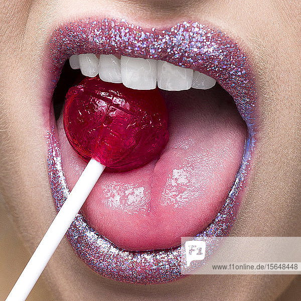 Schimmernde Lippen beißen auf Lollipop